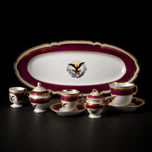 Generated with Kive.ai - Replace the white sculpture with the porcelain service from the reference image a large oval platter in the back with matching cups and lidded pieces arranged across the front. Mat